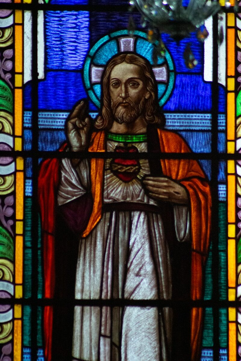 A stained glass window with jesus holding a cross
